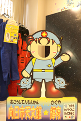 展示室にある天文館のキャラクター輝夜くんの顔出し看板と宇宙飛行士訓練服の写真