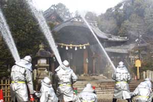 （写真）訓練火災を想定した向日神社・拝殿に向けて勢いよく一斉放水。
