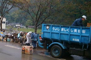 （写真） 舞鶴市での清掃作業。膨大なゴミを手作業でダンプに積みこむ