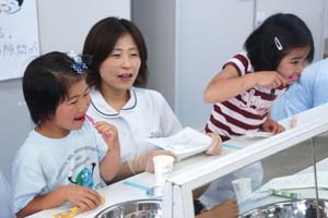 （写真）歯科衛生士の指導を受けながら、ブラッシングをする子どもたち