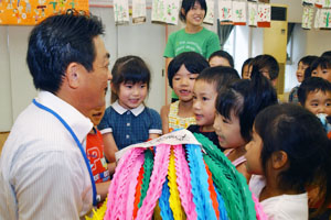 （写真）園児から折り鶴を受け取る久嶋市長