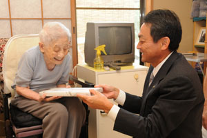 （写真）100歳を迎えられた清水トミさんに記念品を贈呈する久嶋市長