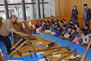 （写真）資料館のボランティアスタッフから説明を受ける小学生