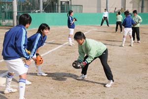 （写真）京都西山高の選手にゴロ捕球の指導を受ける参加者たち
