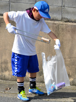（写真）空き缶を回収する子ども