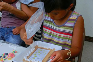 （写真）シリコンのホイップクリームで飾り付けする児童