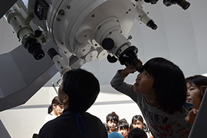 （写真）望遠鏡をのぞく子ども