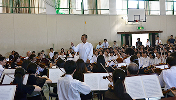 （写真）各学年の代表生徒がオーケストラを指揮