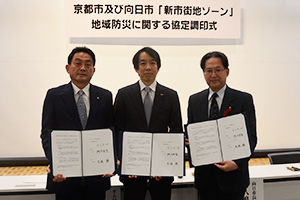 （写真）宮田喜一郎オムロンヘルスケア株式会社代表取締役社長、藤田裕之京都市副市長、久嶋務向日市長が協定書に調印しました。